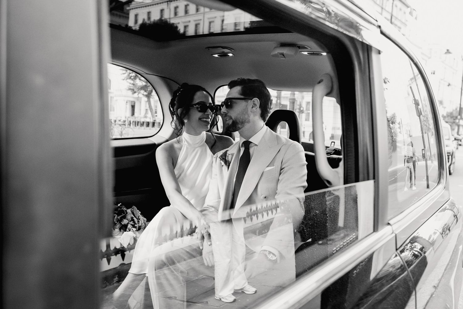 Bride and groom share an intimate moment inside a vintage black cab on their wedding day.