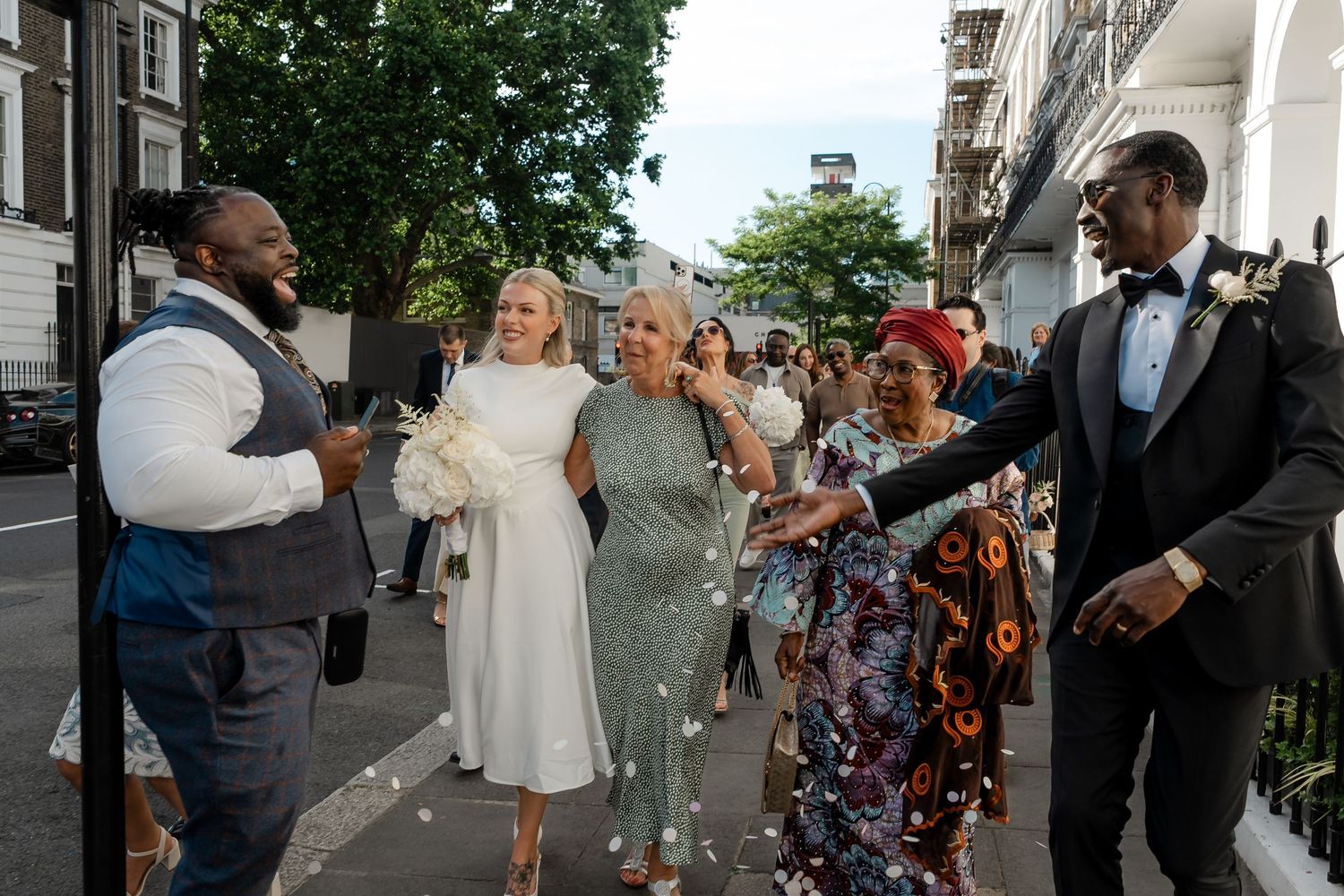 Bride and groom greeted with confetti by family outside a London street after their wedding.
