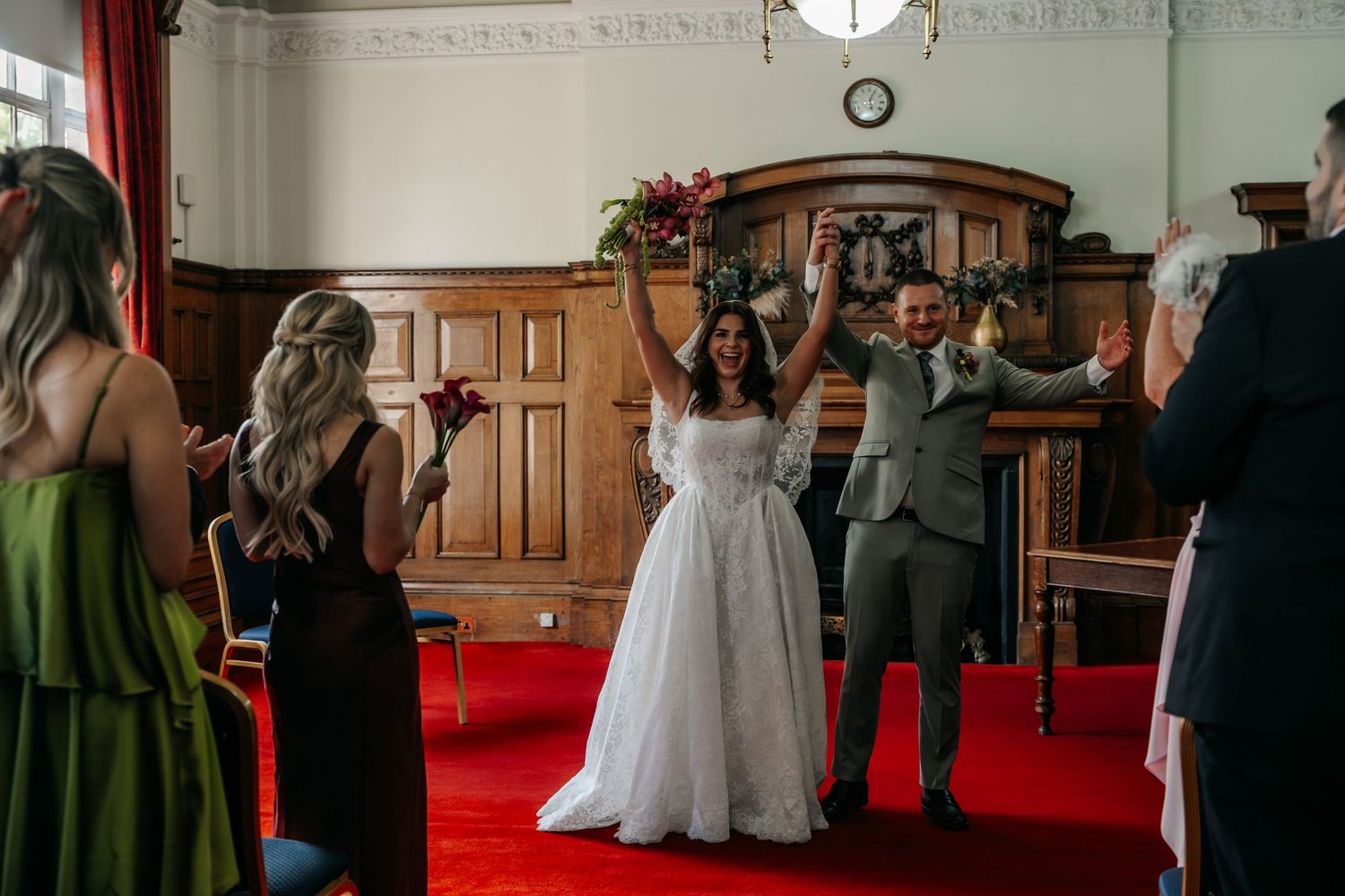 Elated bride raising arms in celebration with groom at altar during wedding ceremony.