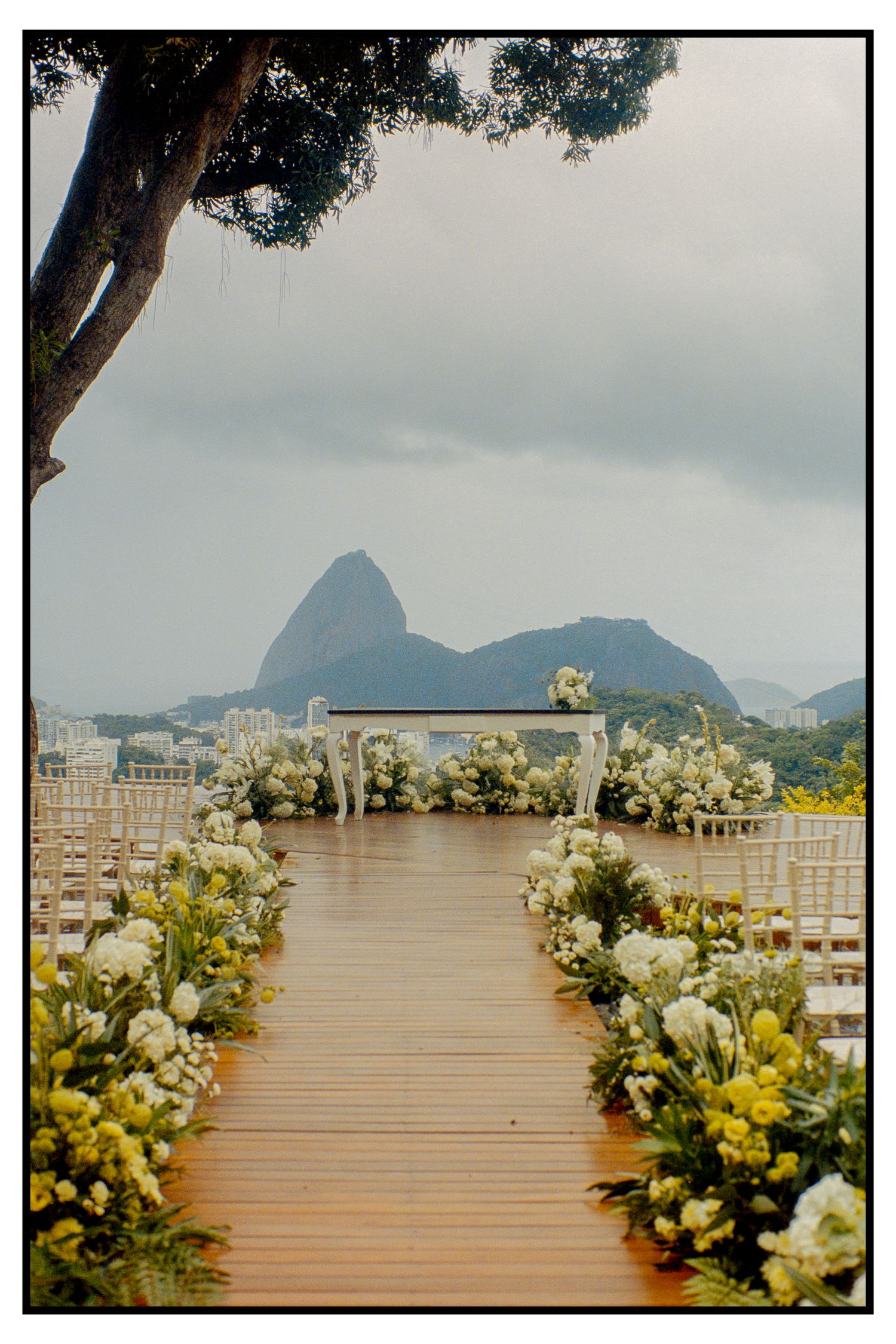 Elegant outdoor wedding aisle lined with white flowers leading to altar with Sugarloaf Mountain view.