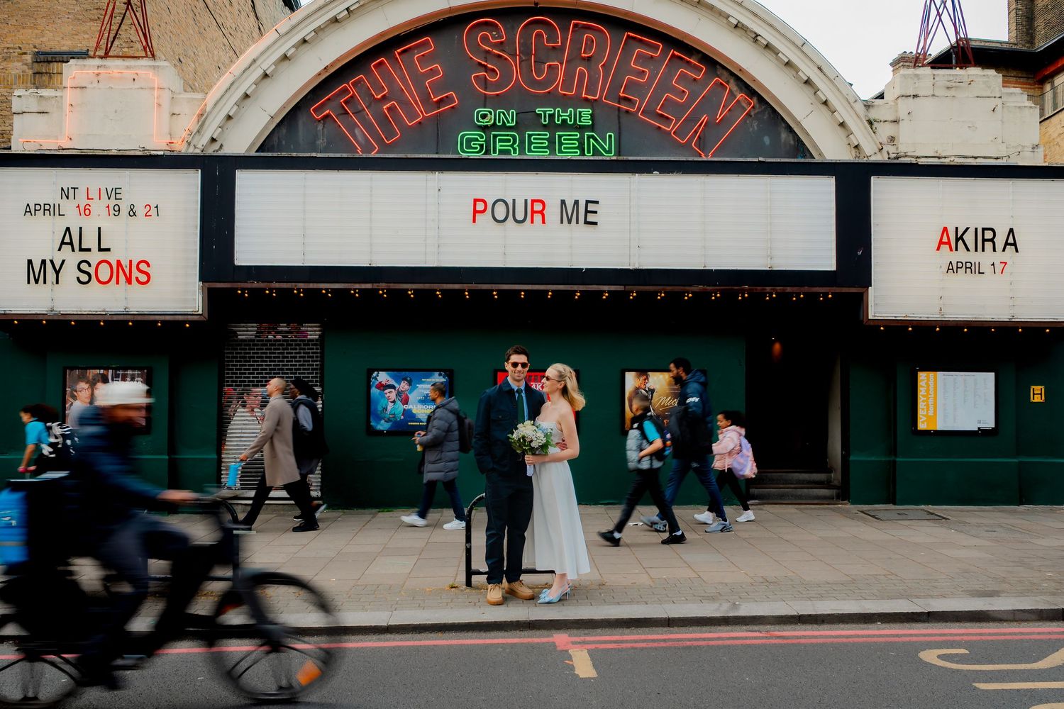 Newlyweds posing outside The Screen on the Green cinema in Islington on wedding day.