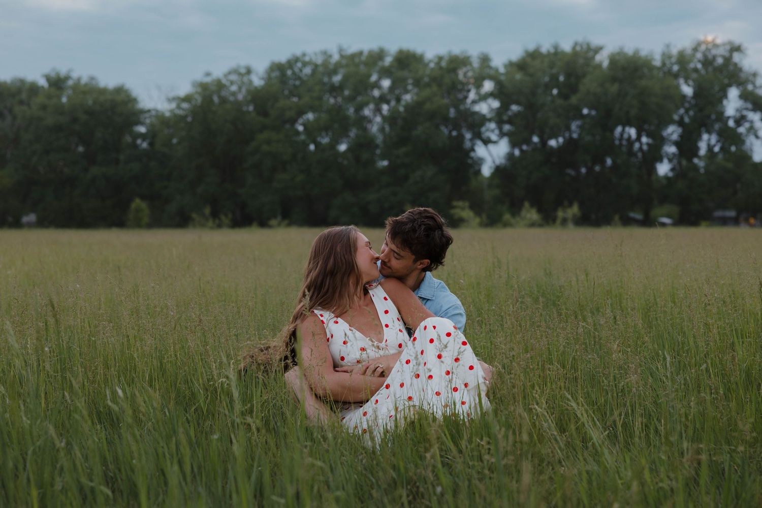 Romantic portrait of a couple embracing in tall grass during blue hour