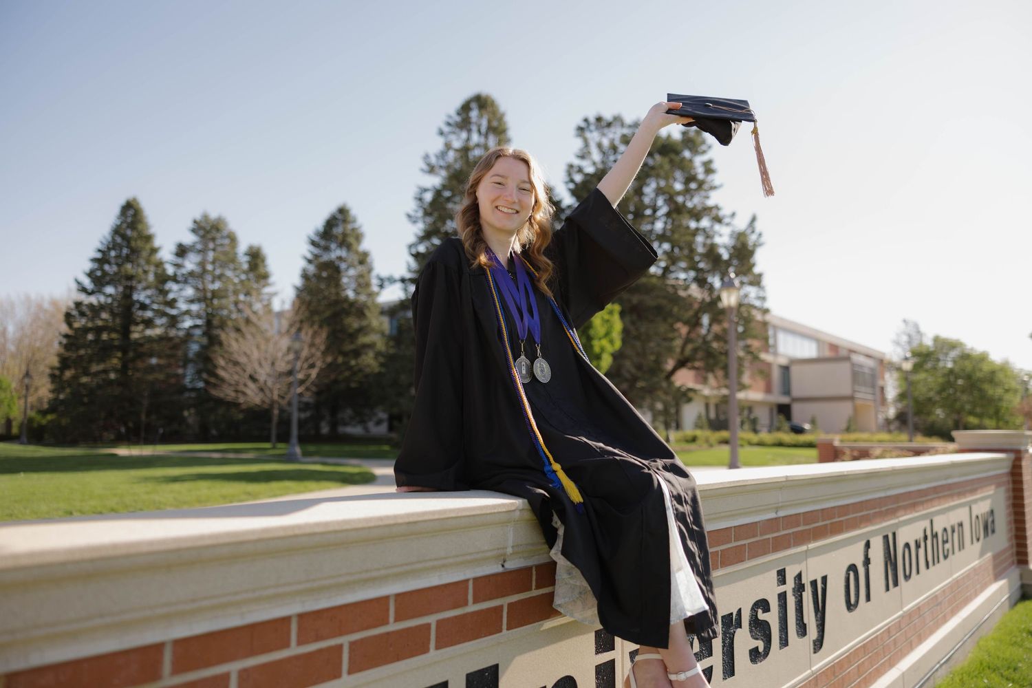 Senior portrait of girl sitting on a brick wall