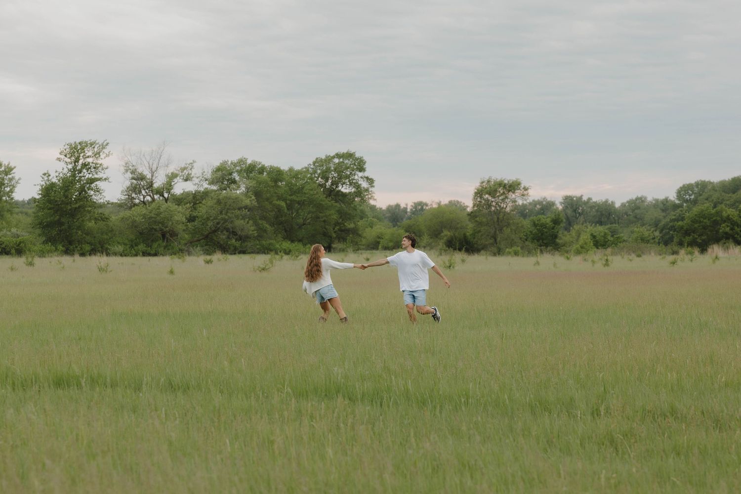 omaha couple frolicking in an open field during golden hour