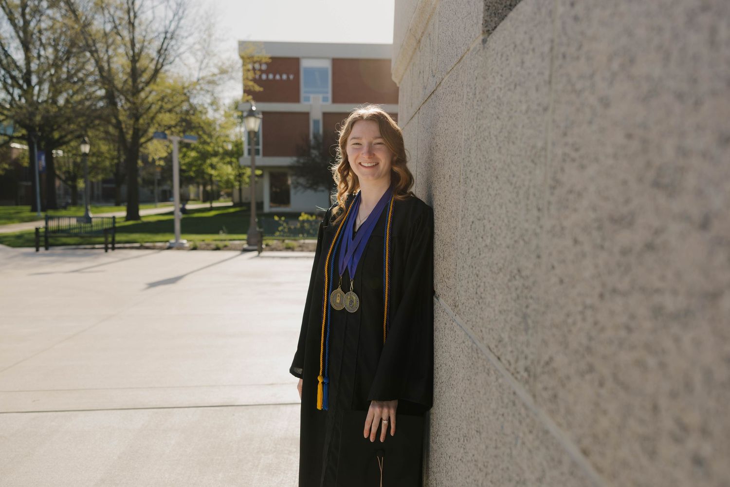 College senior posing near University of Northern Iowa clock