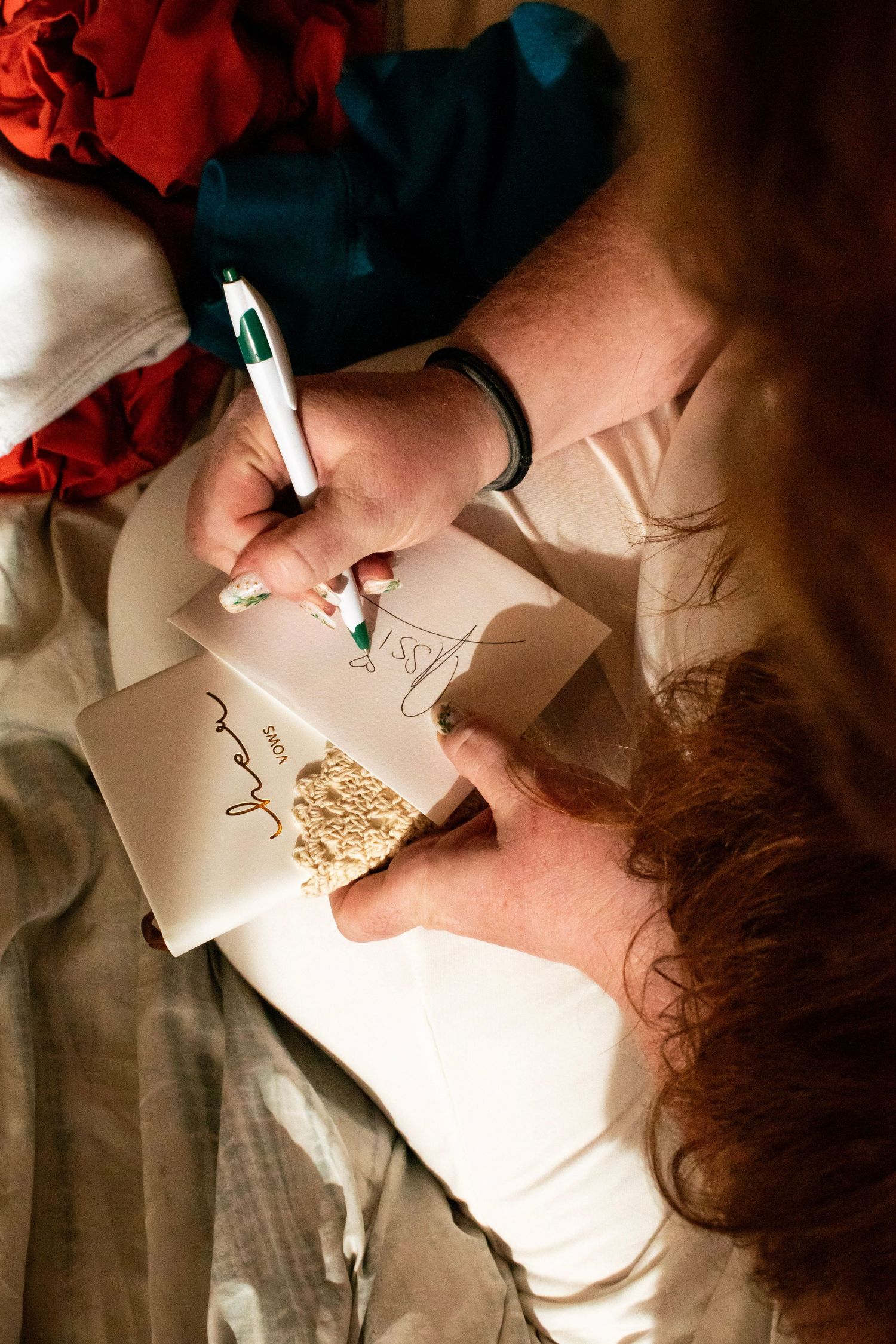 Close-up of person writing a wedding card message with green marker in warm indoor lighting.