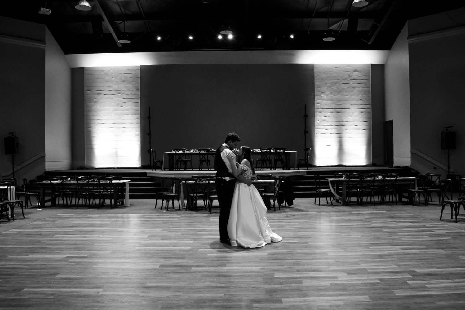 Black and white photo of a couple sharing their final private dance on an empty dance floor at a wedding reception at Creekside Event Center