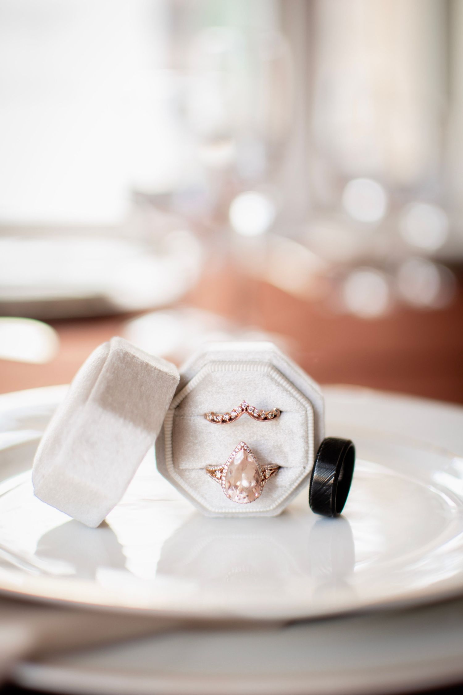 Rose gold engagement ring with morganite stone and matching band displayed in an octagonal velvet ring box on white plate.