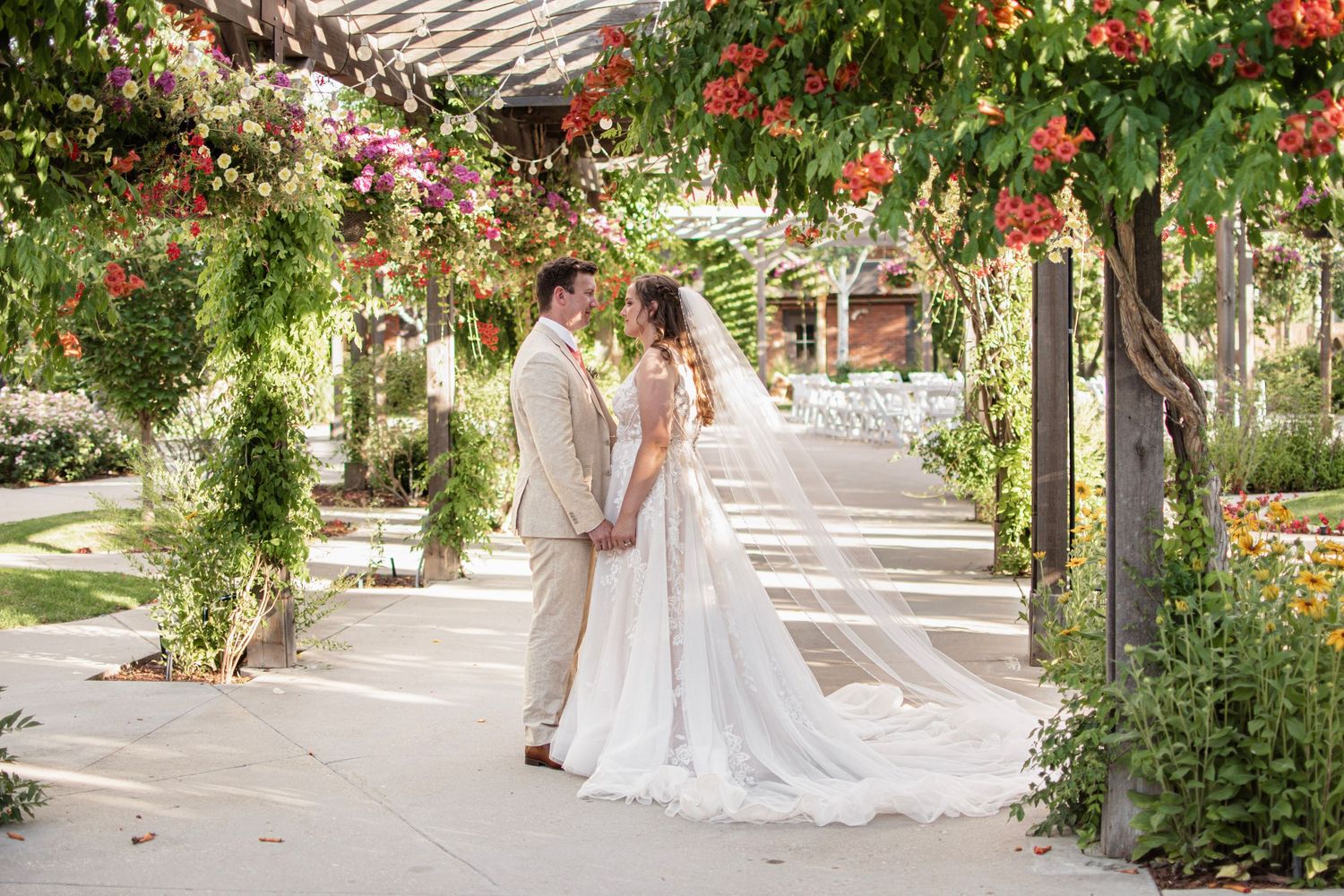 Bride and groom hold hands under a floral arch in a lush garden wedding ceremony setting at Brookside Gardens in Berthoud, CO