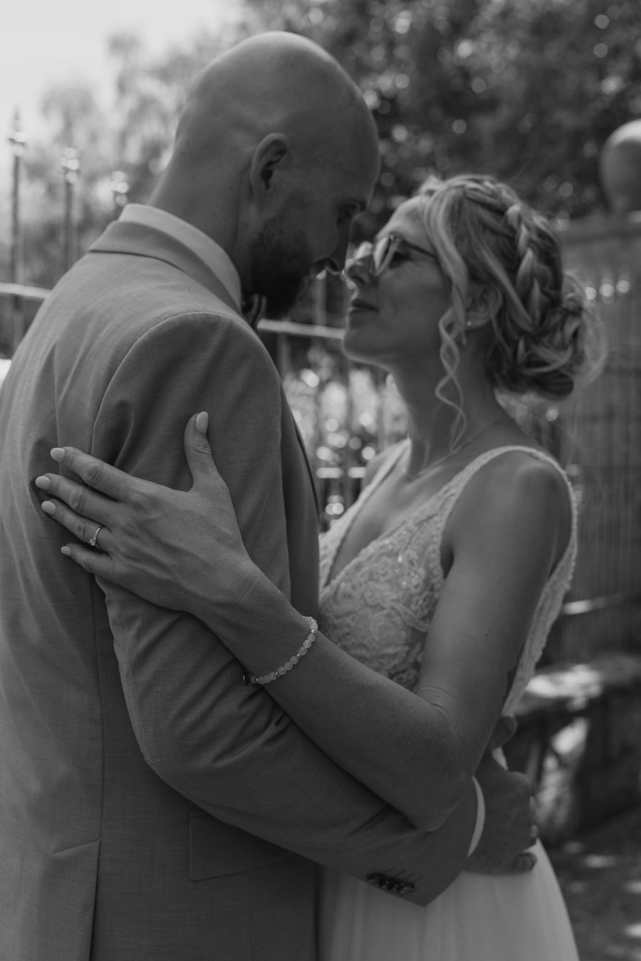 Bride and groom share intimate moment, foreheads touching in black and white photo.