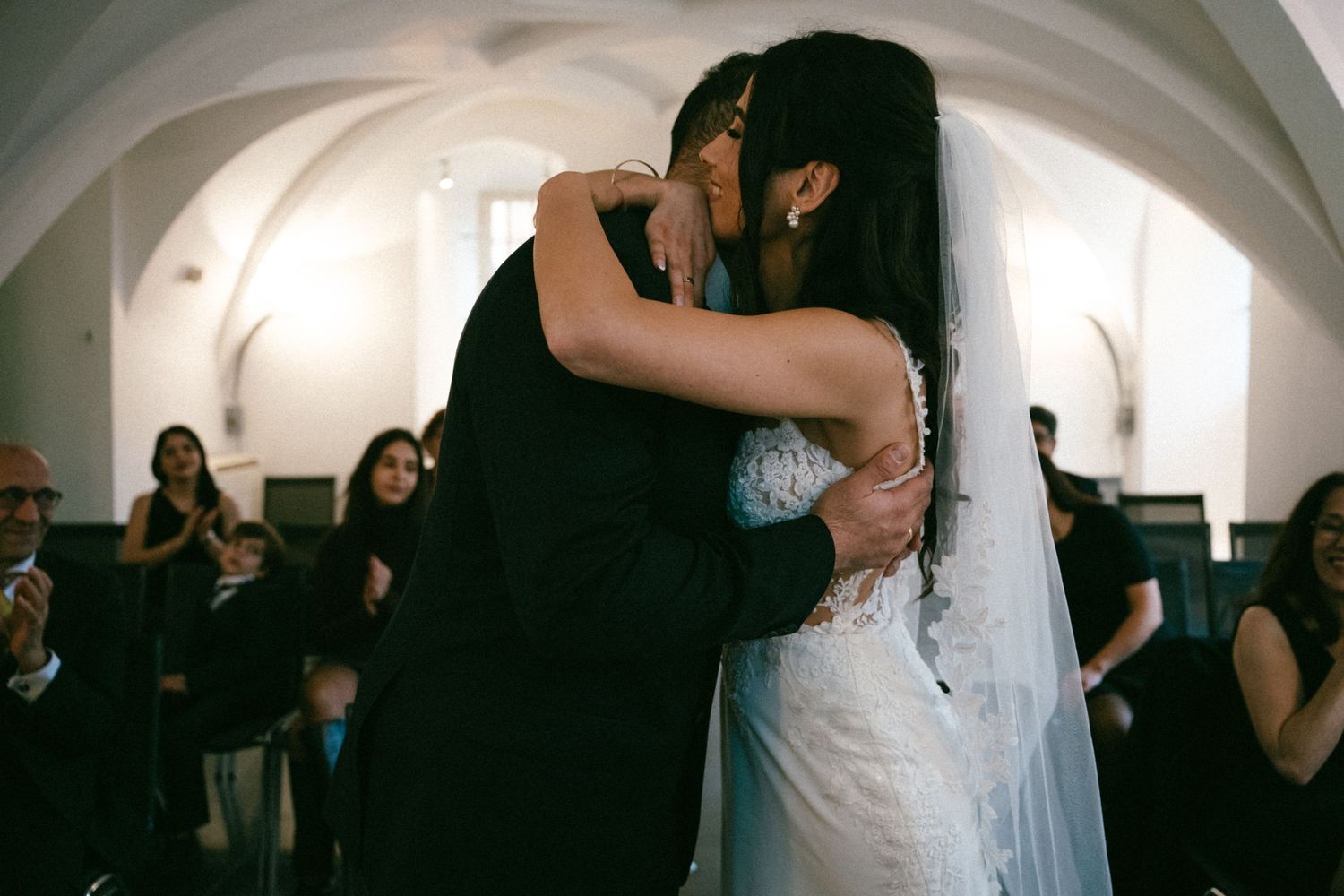 Bride and groom share tender first dance embrace in elegant arched wedding venue.