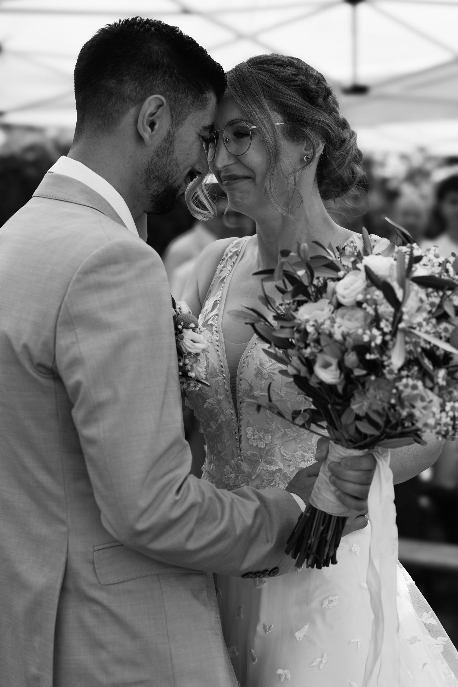 Bride and groom share tender moment with floral bouquet at wedding reception.
