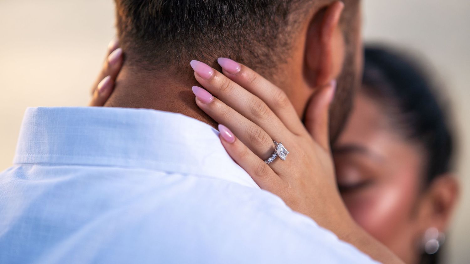 Close-up of an engagement ring as a couple embraces