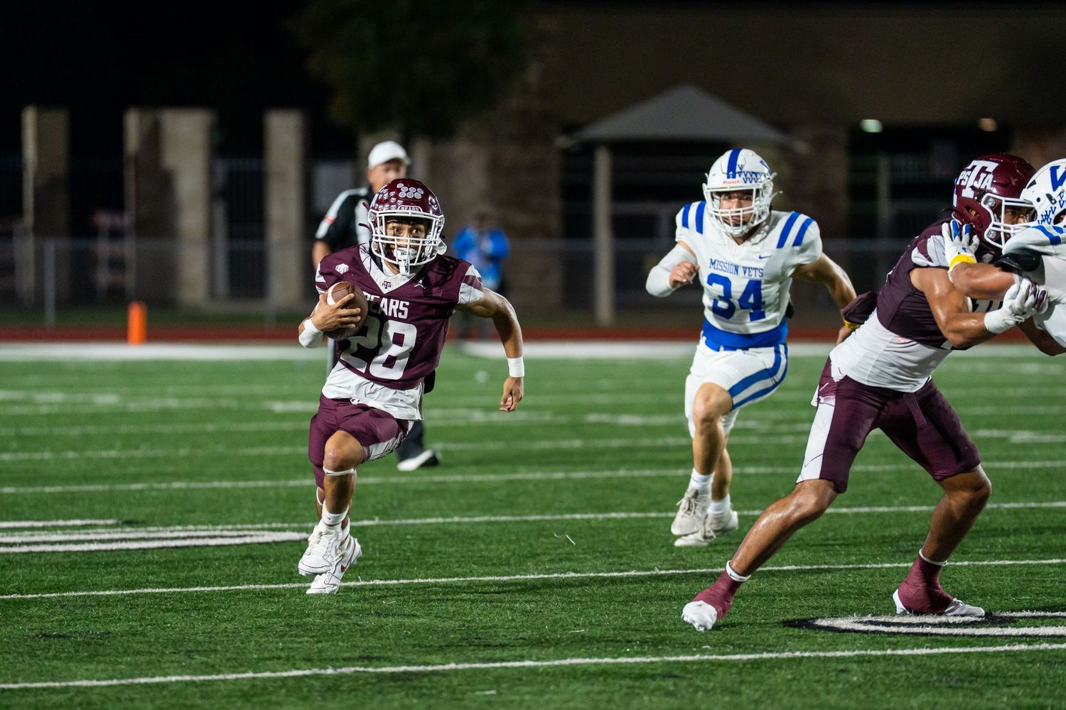 High school football player running with the ball during a nighttime game