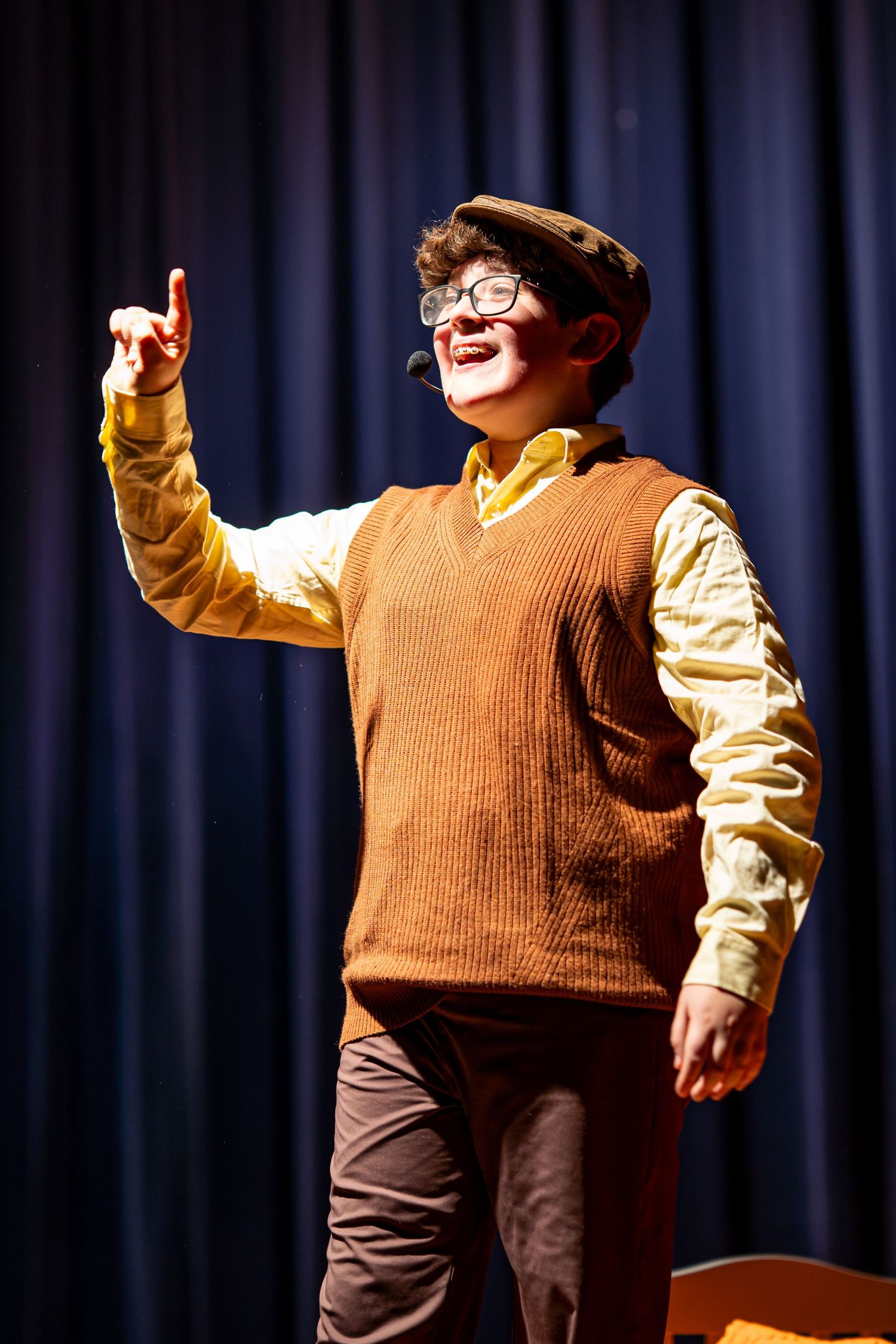 Young theater performer smiling and singing during a live stage performance