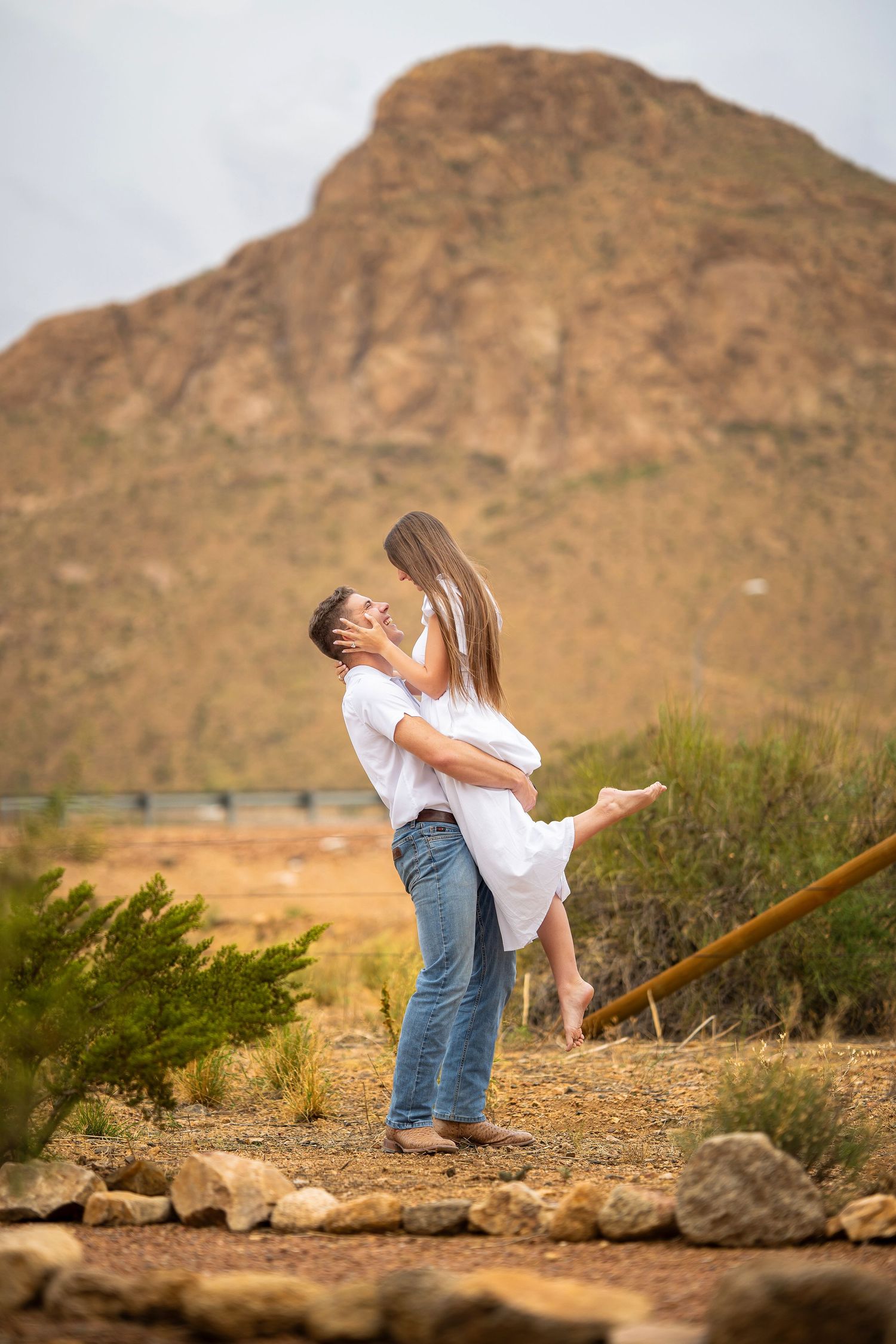 Couple laughing as he lifts her during an outdoor engagement session