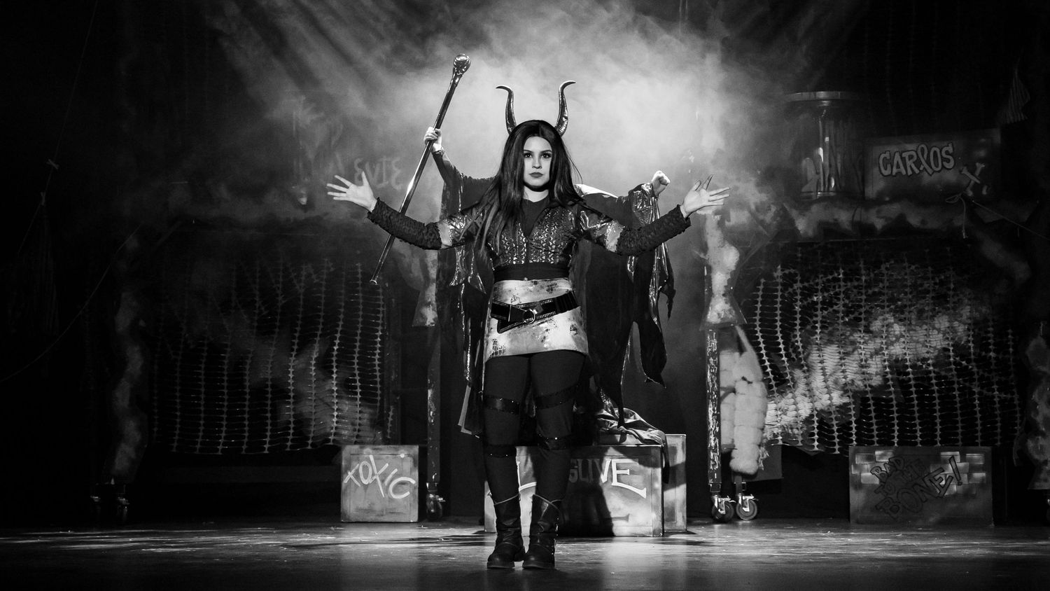 Black-and-white photograph of a theatrical performance with dramatic stage lighting and smoke