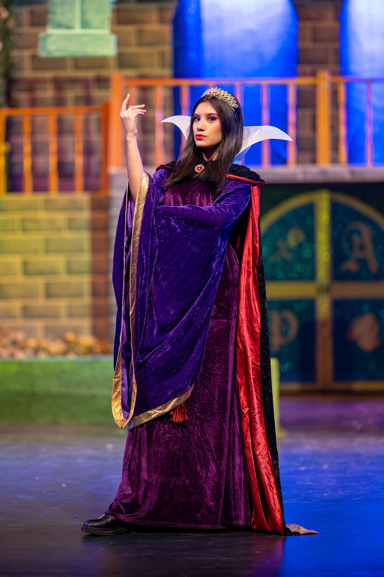 Theater performer in a dramatic purple queen costume during a live stage production