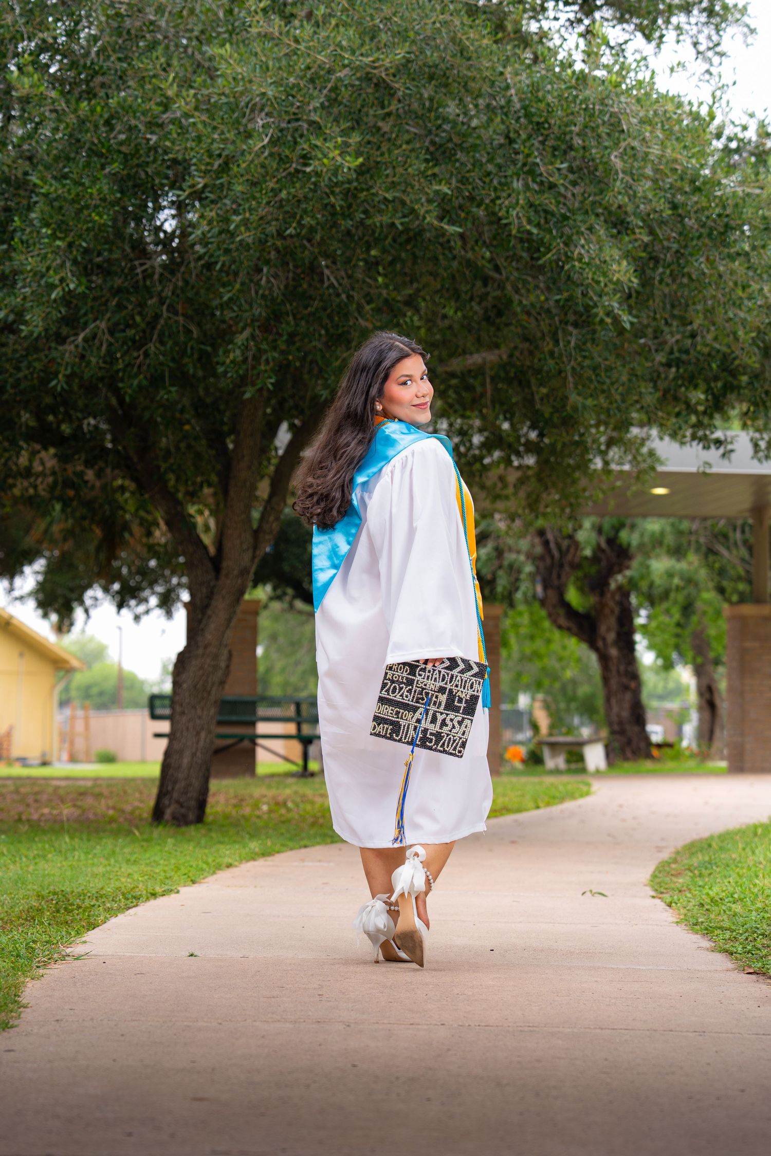 Graduate in a white cap and gown celebrating her graduation outdoors