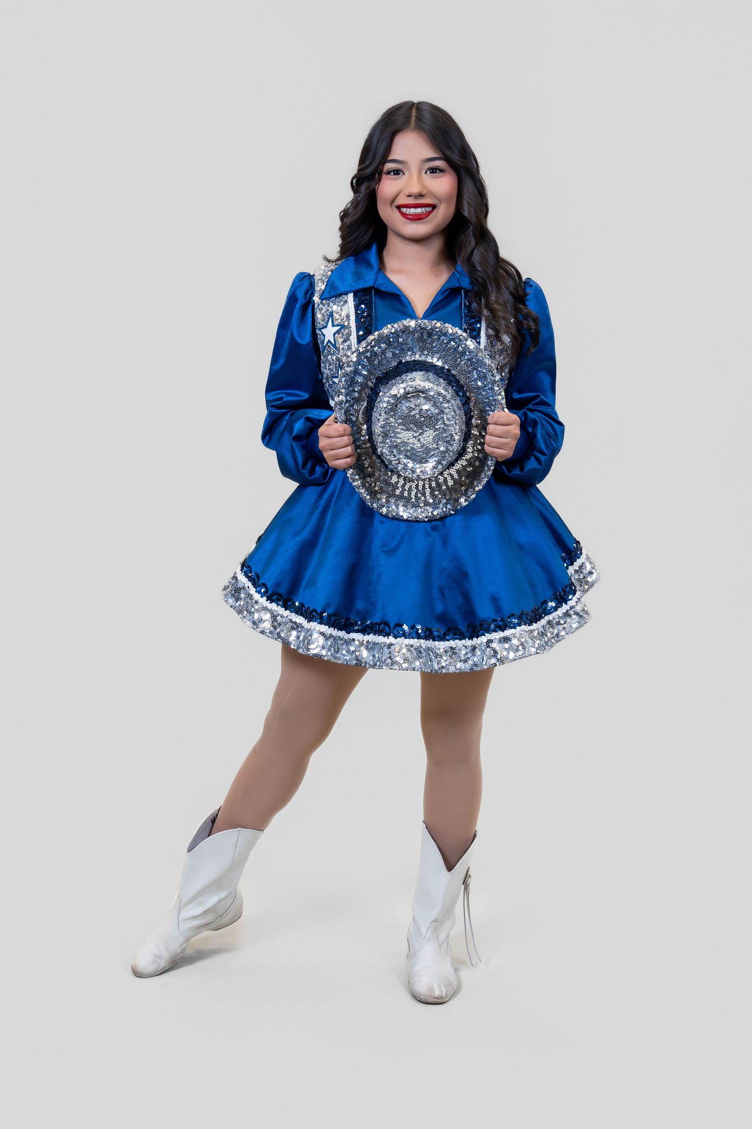 Studio portrait of a performer in a blue and silver dance uniform holding a sequined hat