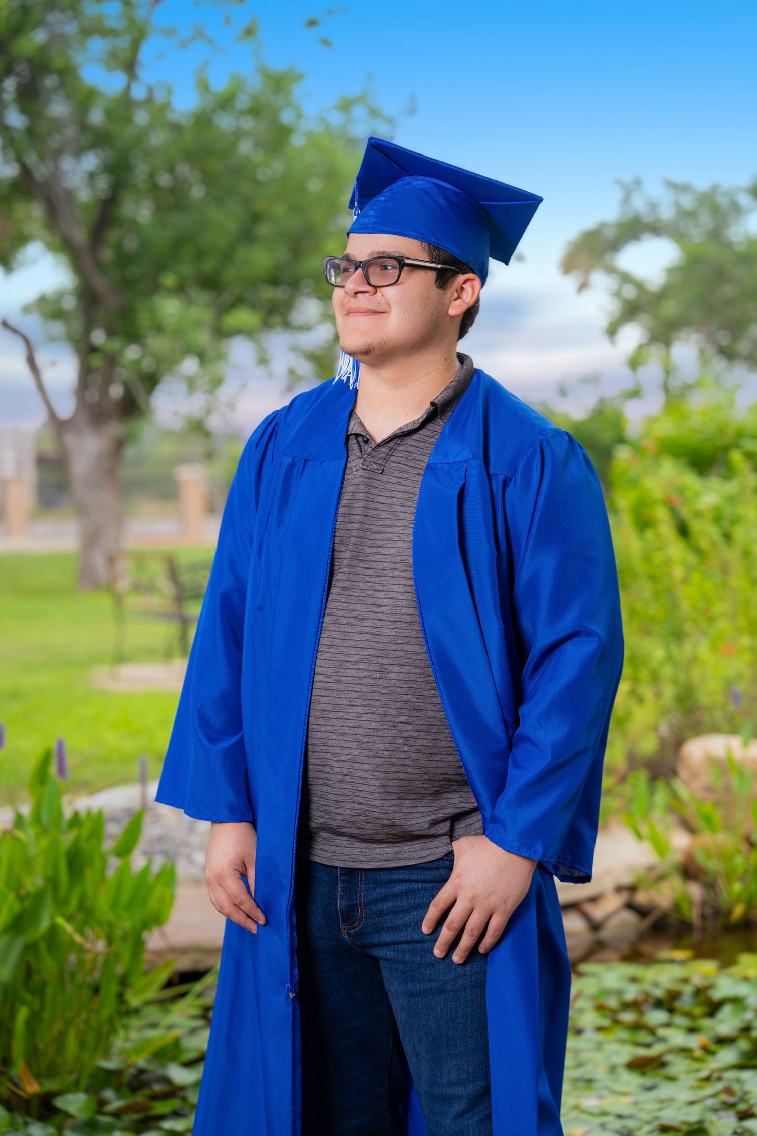 Graduate wearing a blue cap and gown during an outdoor graduation portrait session