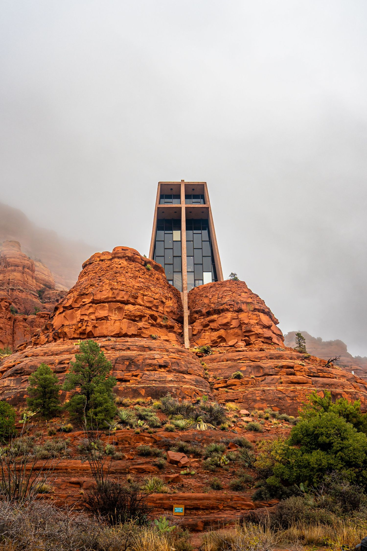 Modern chapel surrounded by red rock cliffs and morning fog