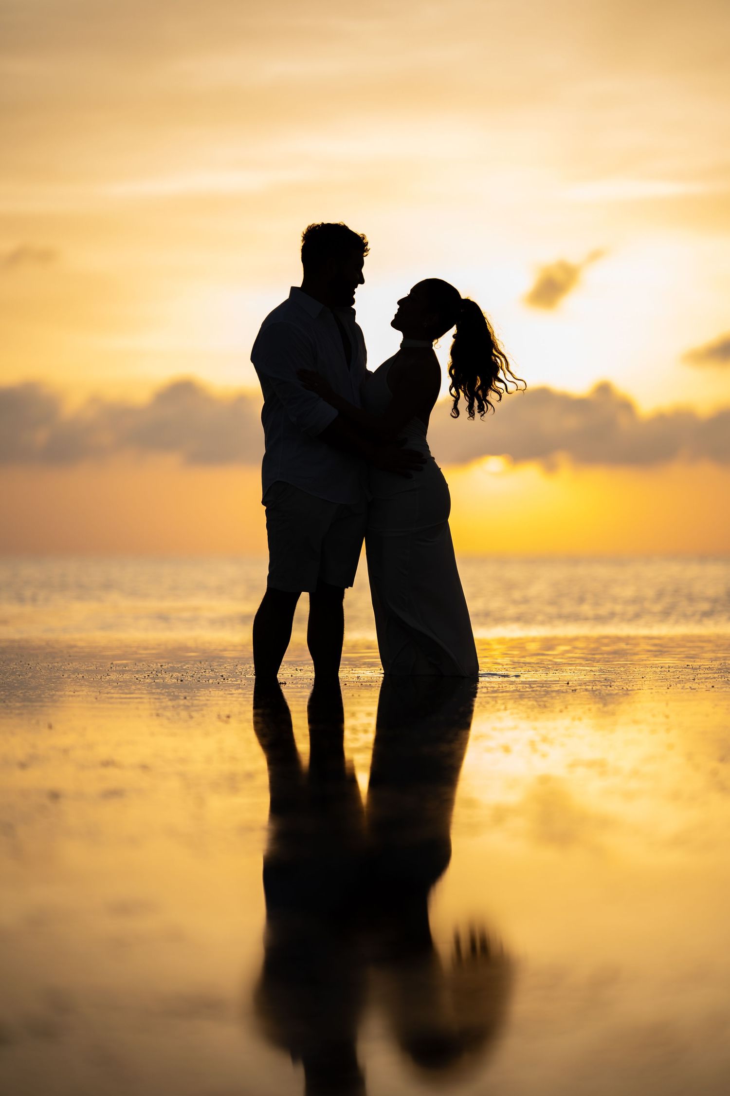 Silhouette of a couple embracing on the beach during a golden sunset
