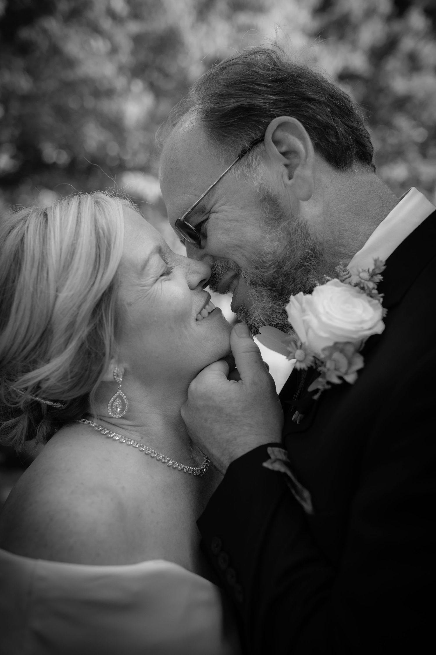 Black and white photo of a bride and groom sharing a tender kiss at their wedding ceremony.