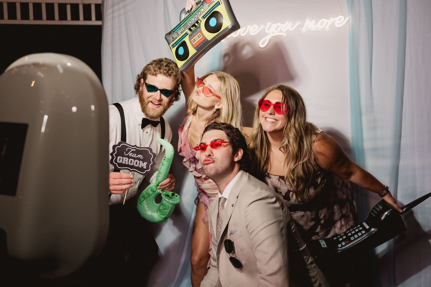 People posing with party props and colorful lighting at a photo booth celebration event.