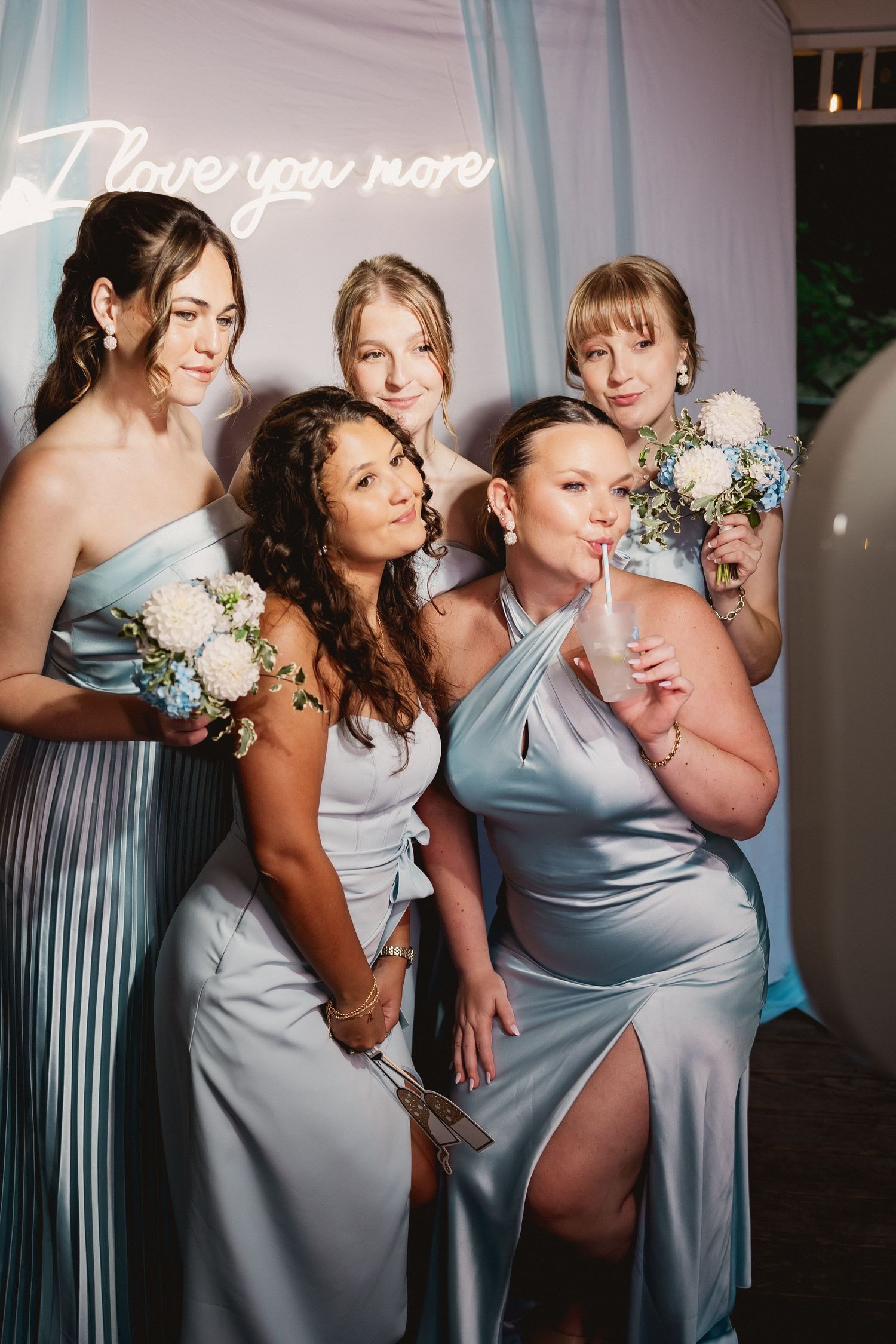 Wedding party members in light blue dresses pose together for fun candid photos.