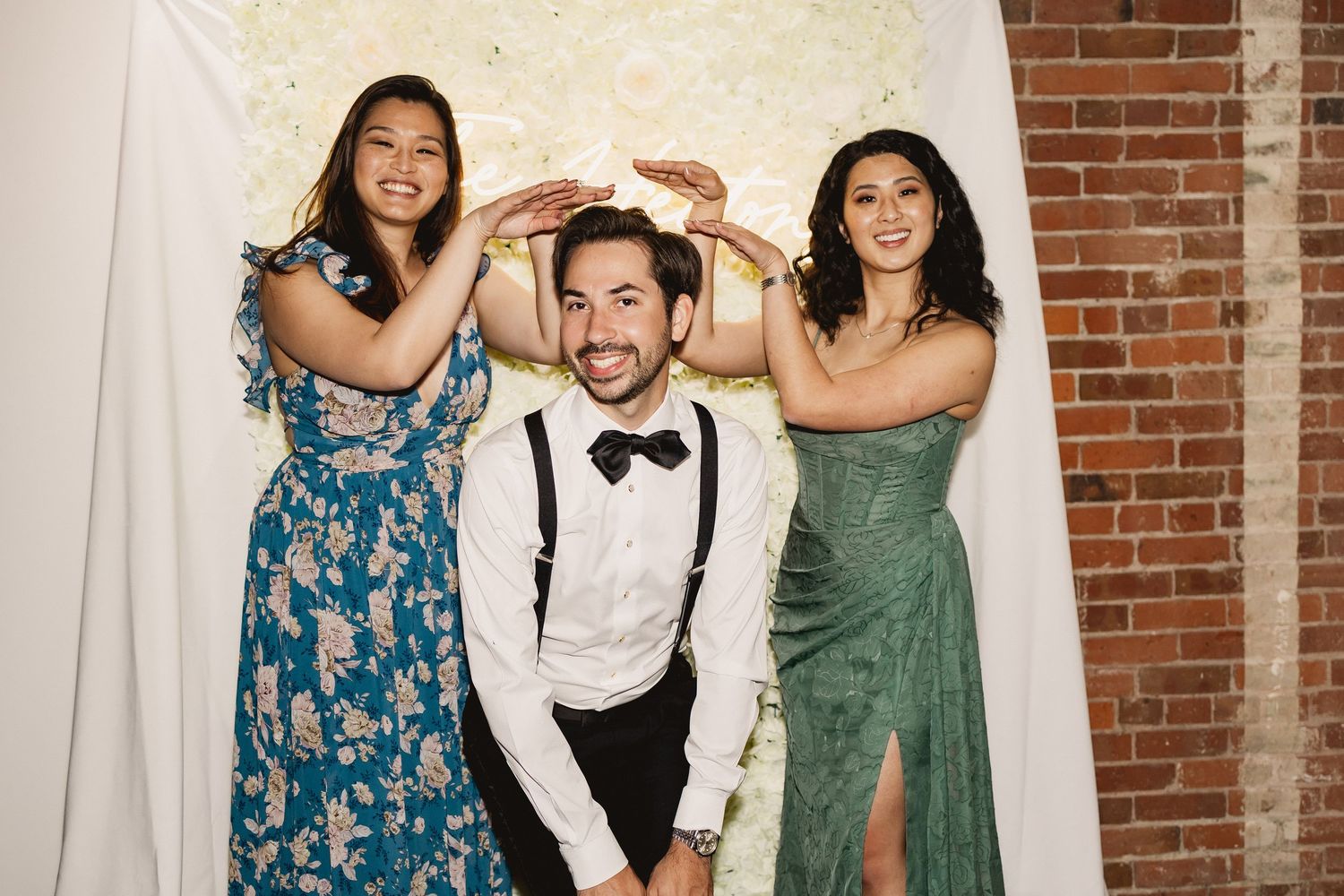 Wedding party poses playfully in front of exposed brick wall at reception venue.