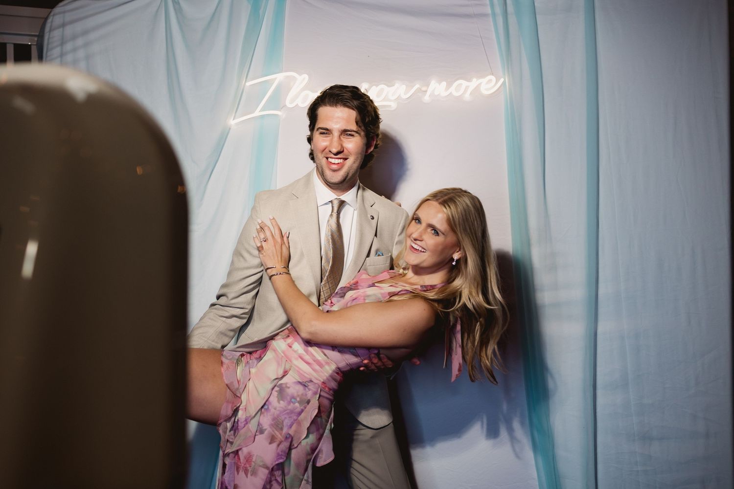 A couple shares a playful and romantic moment dancing together against a blue backdrop.