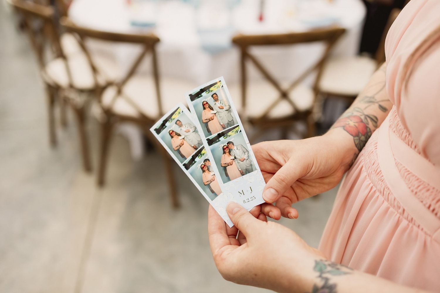 A person in a pink dress holds vintage polaroid photos while sitting in a rustic wooden chair.