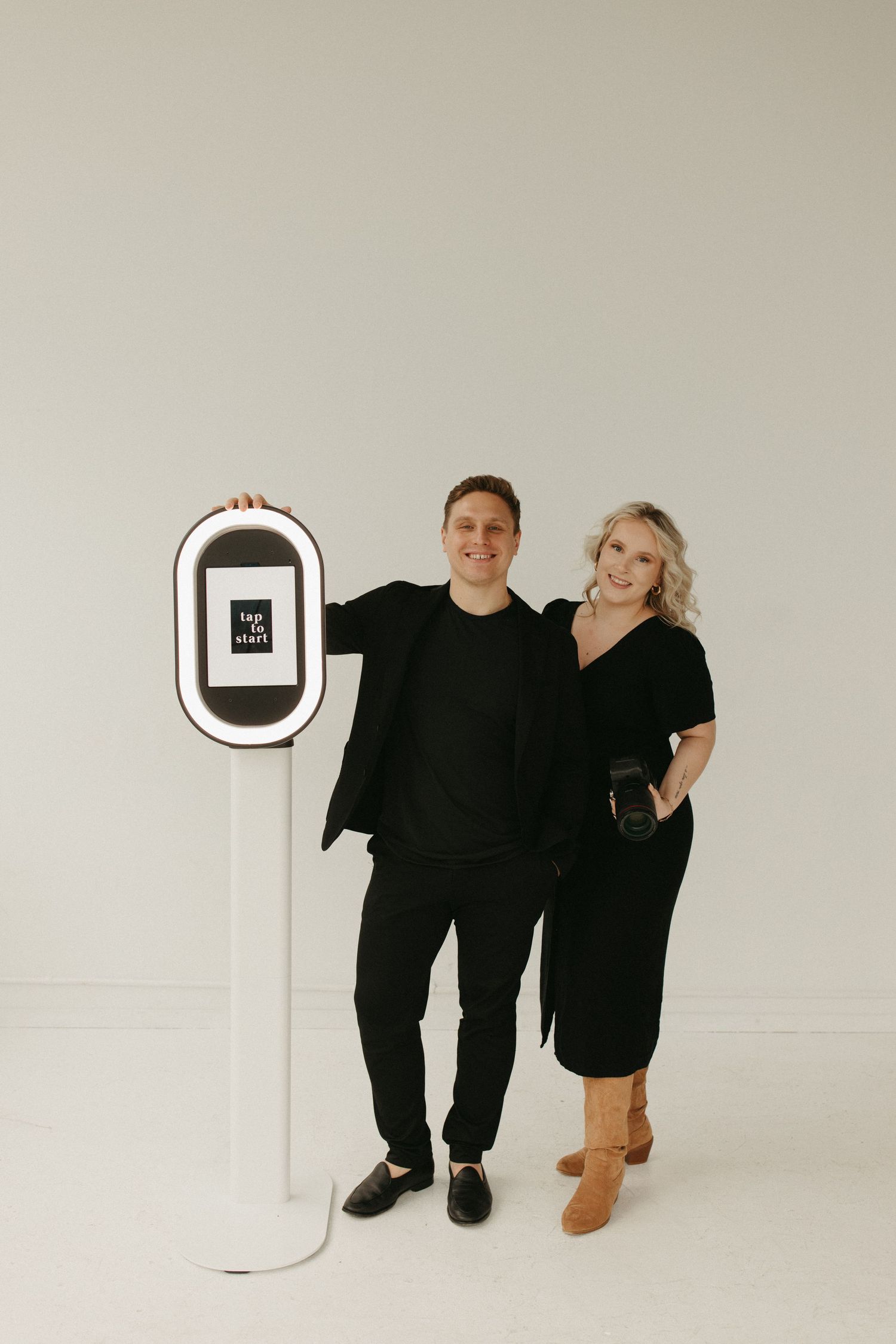 Two people in matching black outfits pose together in a minimalist white studio setting across multiple photos.