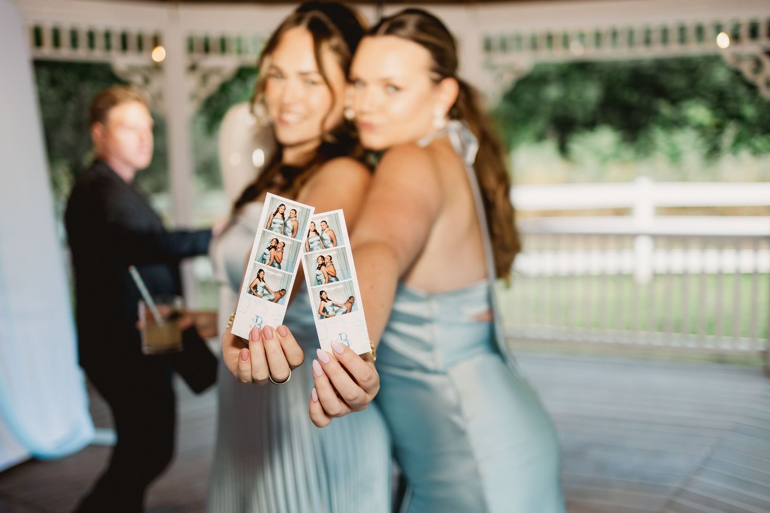Wedding guests raise shot glasses in a celebratory toast during an outdoor reception.