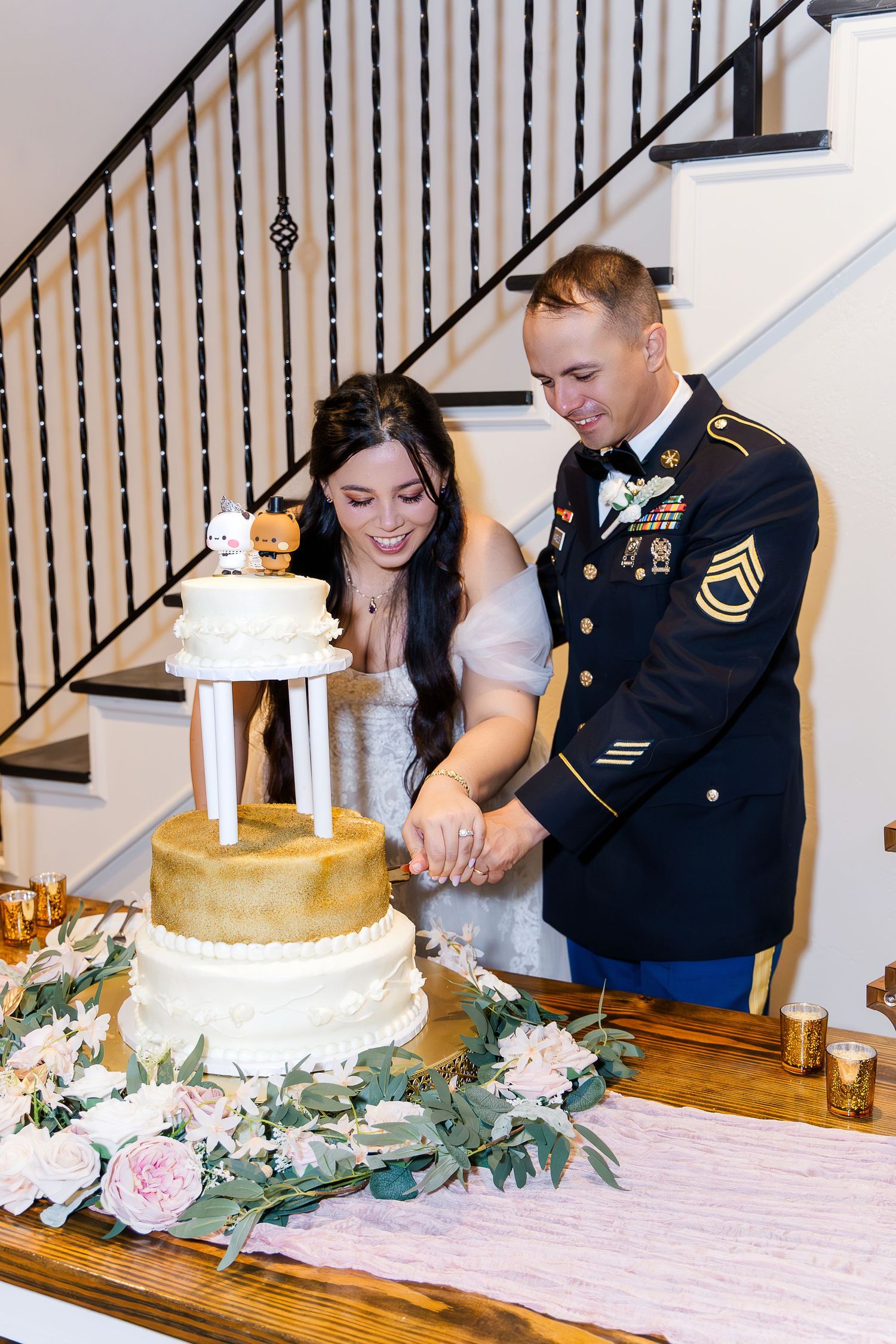 A couple cuts their three-tiered wedding cake decorated with fresh flowers.