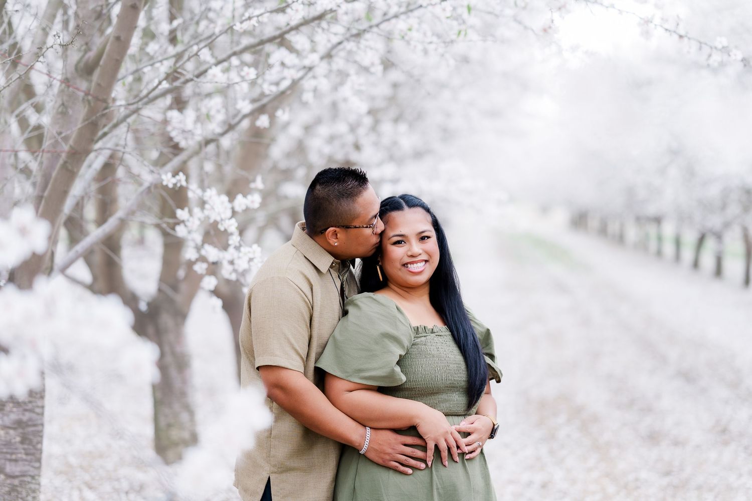 A couple shares romantic moments in a snowy forest setting during their winter engagement photo session.