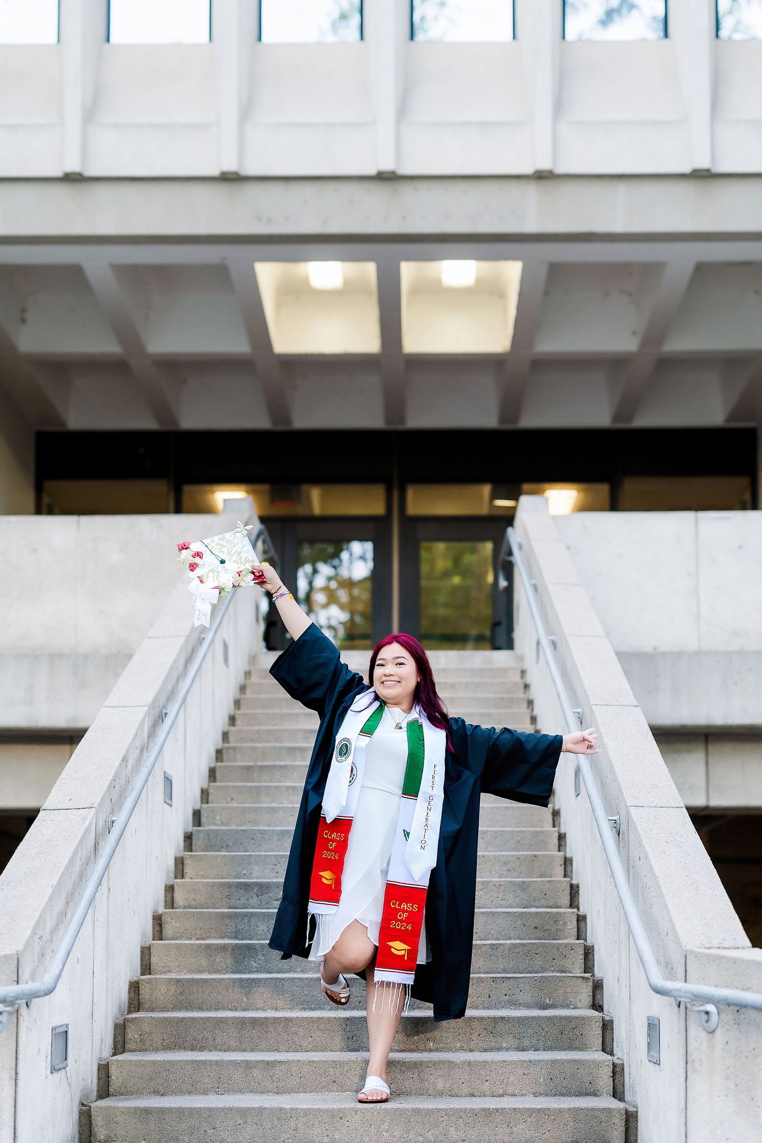 Graduate in black cap and gown celebrating on concrete steps with joyful poses.