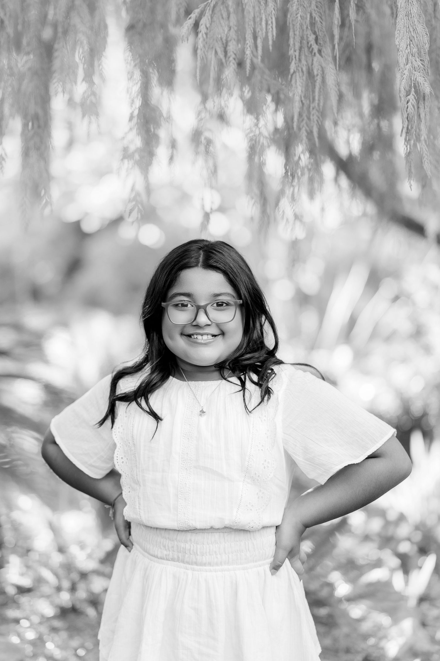 Black and white portrait series showing joyful expressions in a dreamy outdoor forest setting.