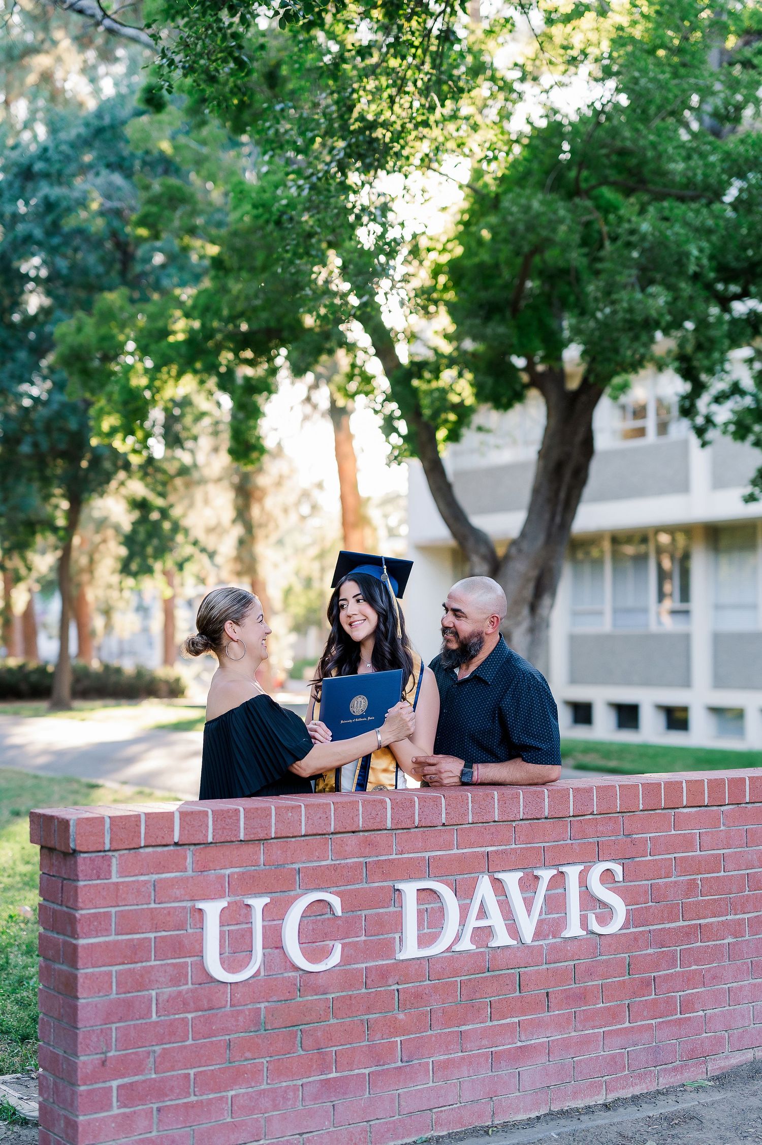 People gathered around the iconic UC Davis brick entrance sign during graduation celebrations.