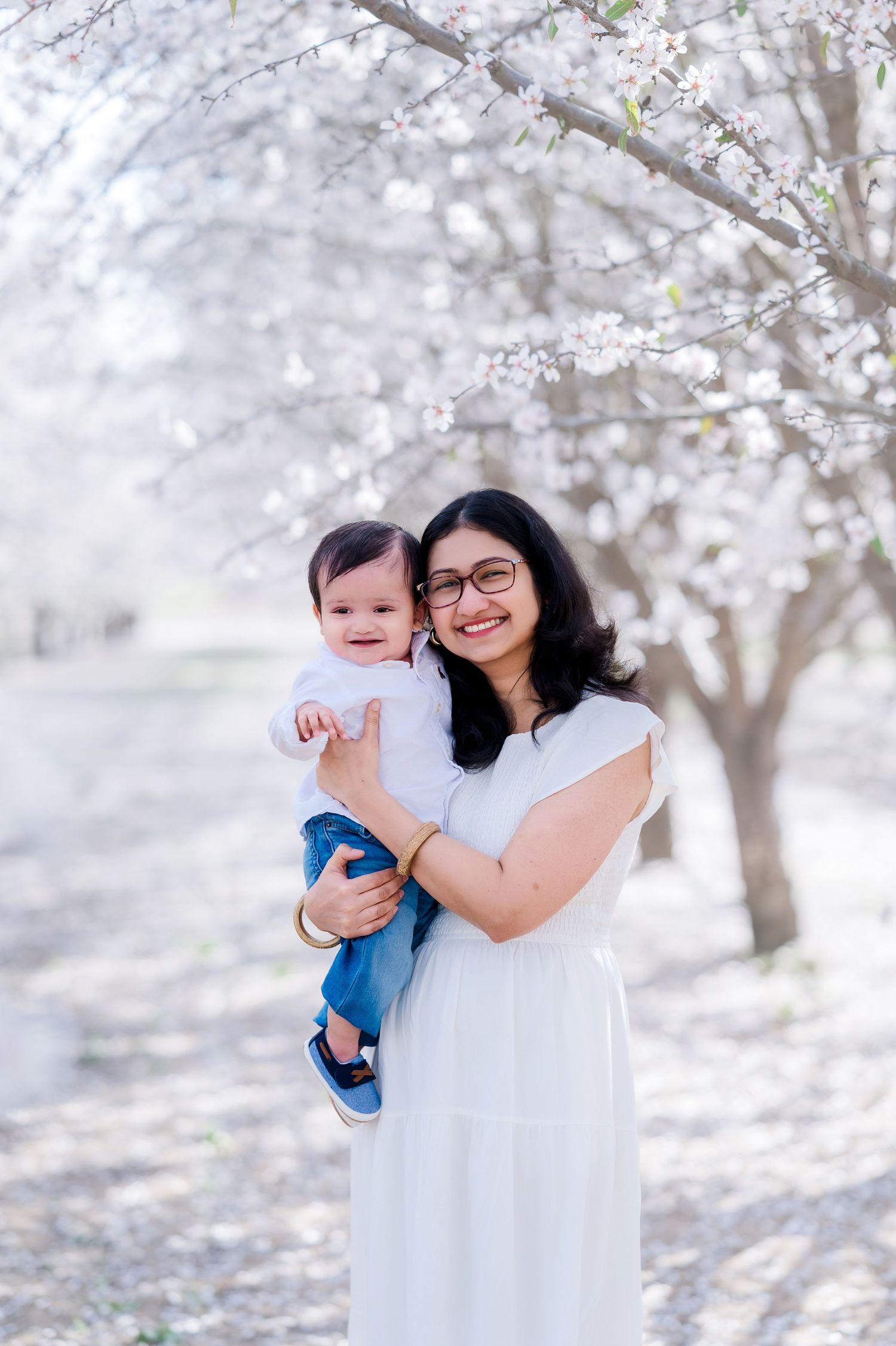 A spring scene with blooming cherry blossoms as two figures stand beneath the delicate white flowers.
