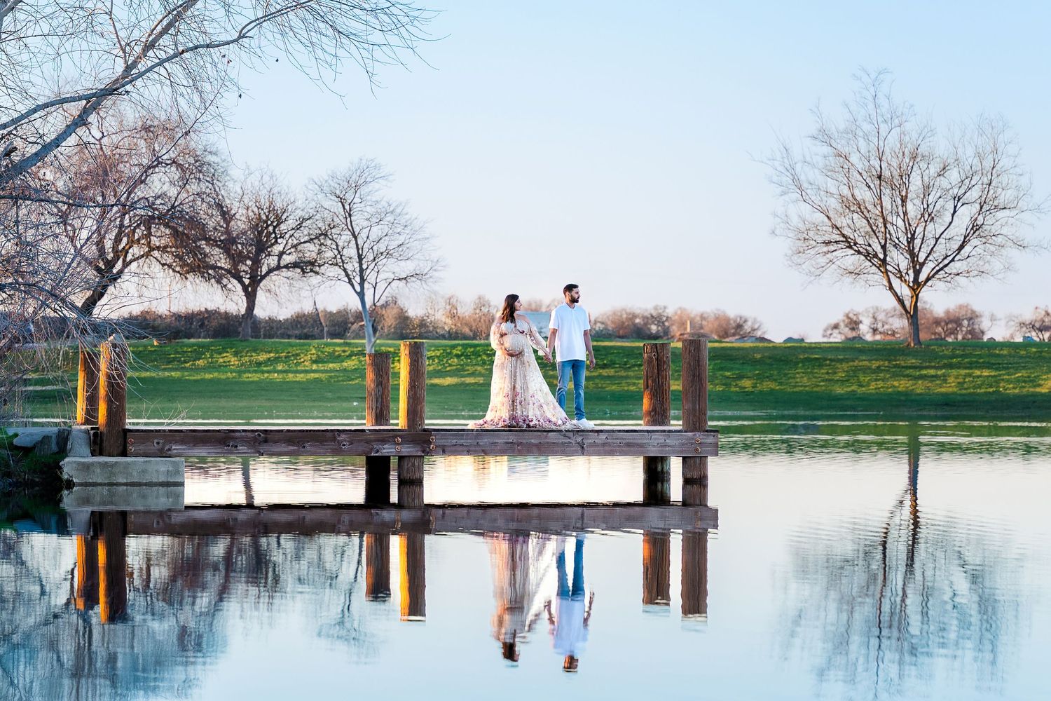 Panoramic view of a serene lake with wooden posts reflecting in the calm water during winter.