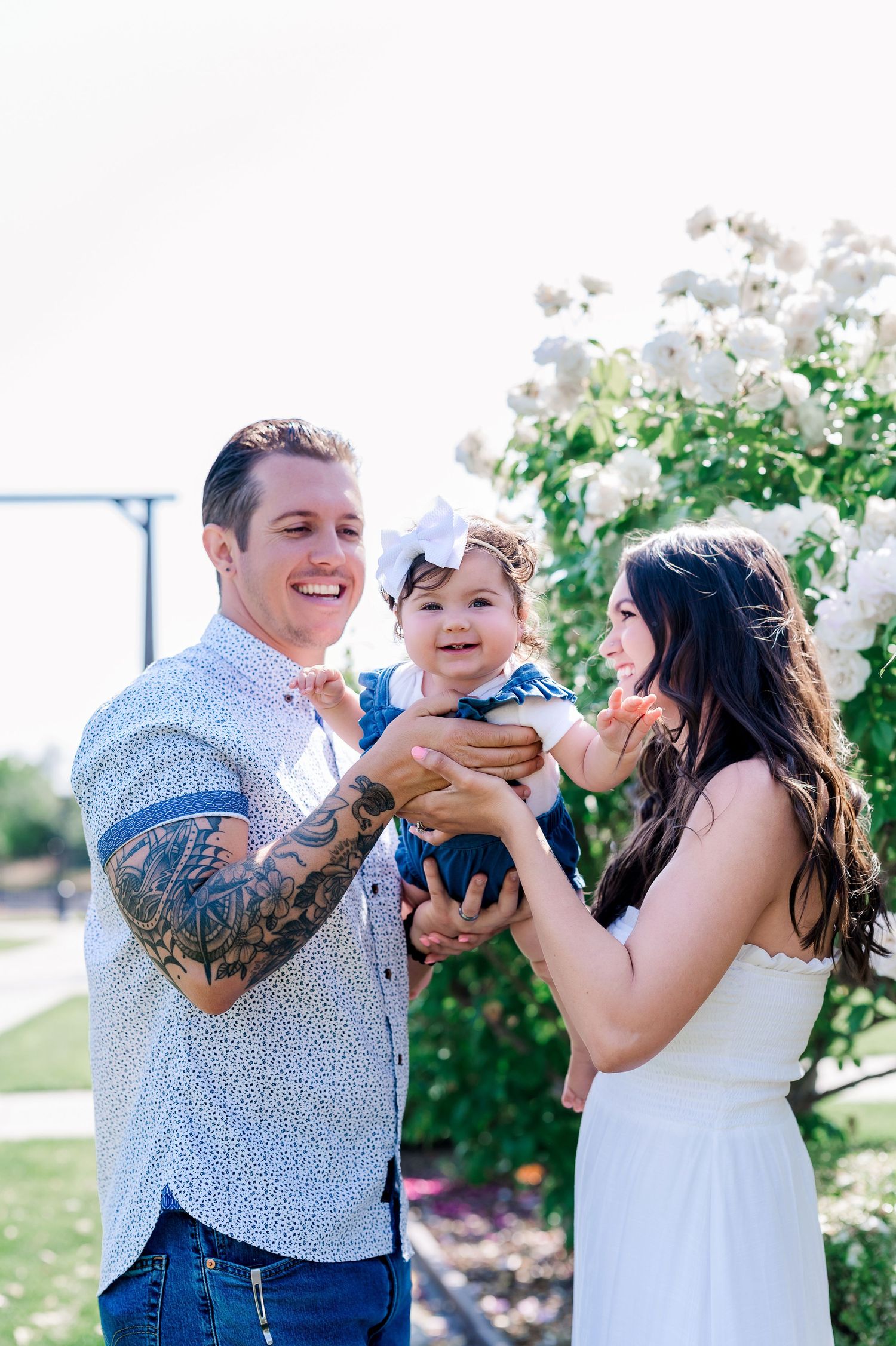 Joyful family moment outdoors with white flowers in background.