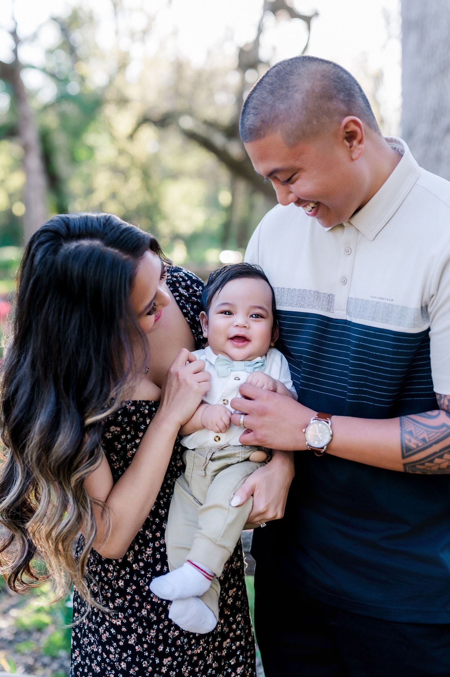 A young family shares an intimate moment together outdoors with their baby wearing white.