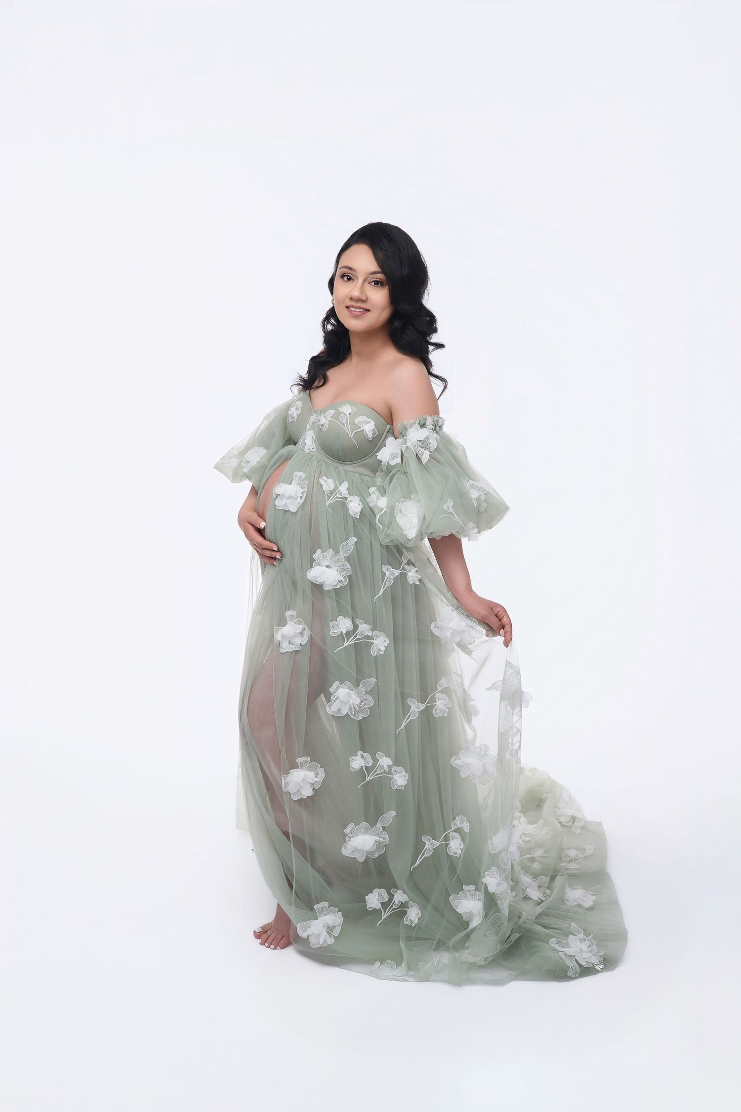 Pregnant woman in sage green floral tulle maternity gown posing gracefully against white background. Sacramento Maternity Photographer