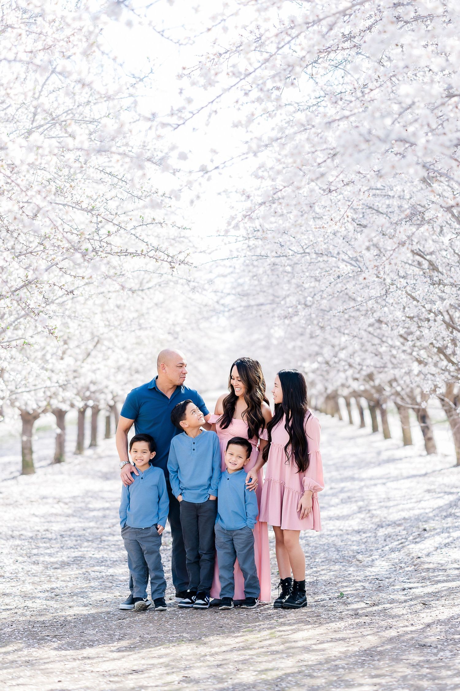 Family portrait under blooming cherry blossom trees in white spring landscape.