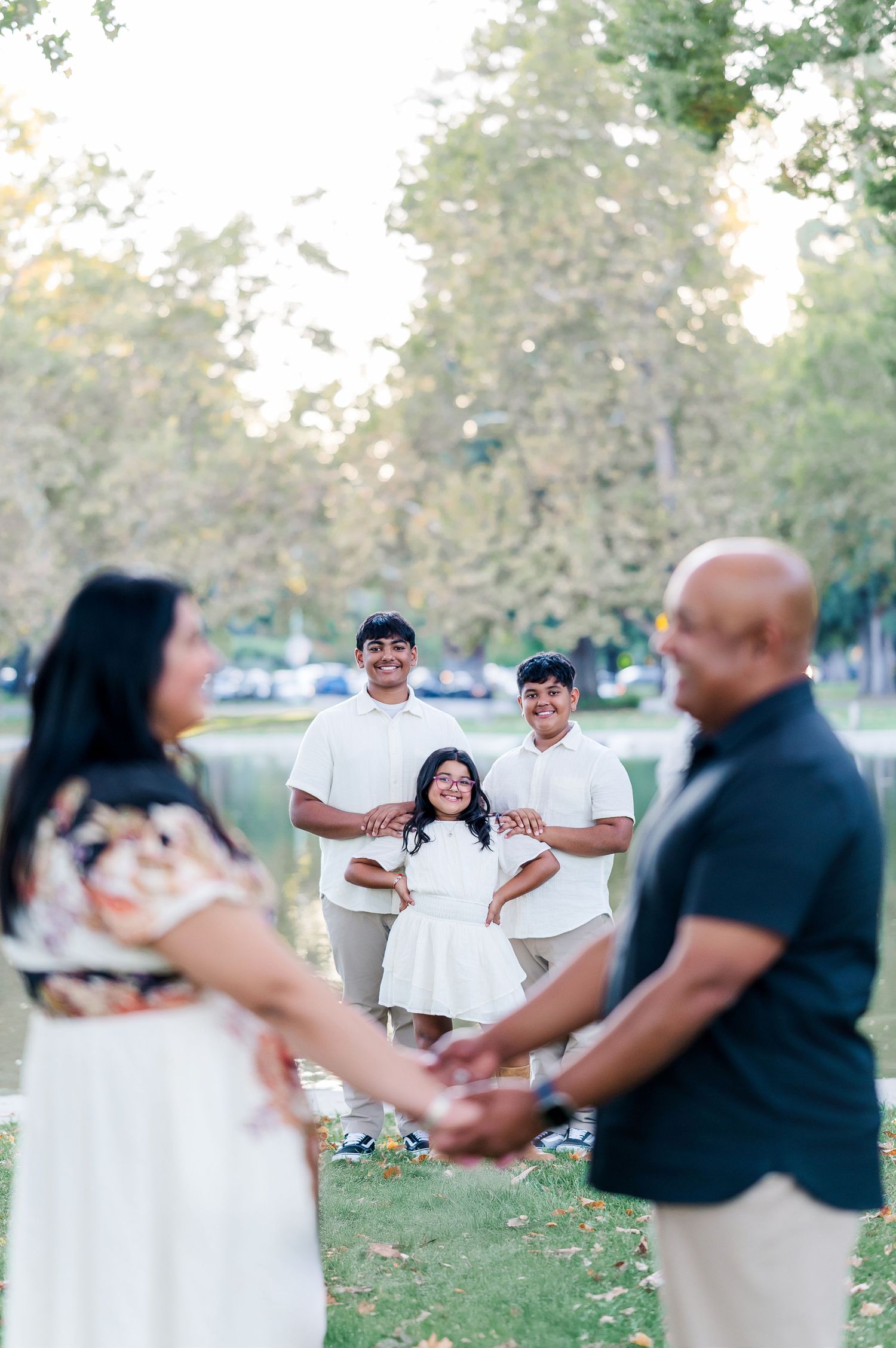 A group of people dancing together in a park setting wearing black and white outfits during a summer gathering.