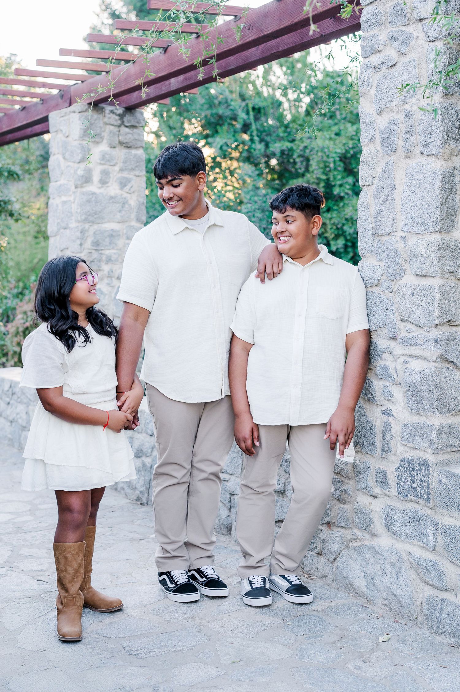 Casual portrait session against stone wall with people in matching white shirts and khaki pants.