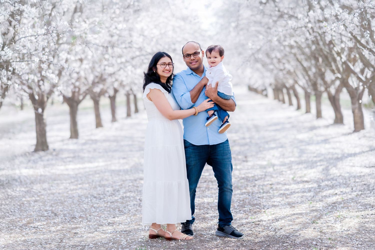 A couple shares tender moments in a snowy orchard with trees creating a romantic winter backdrop.