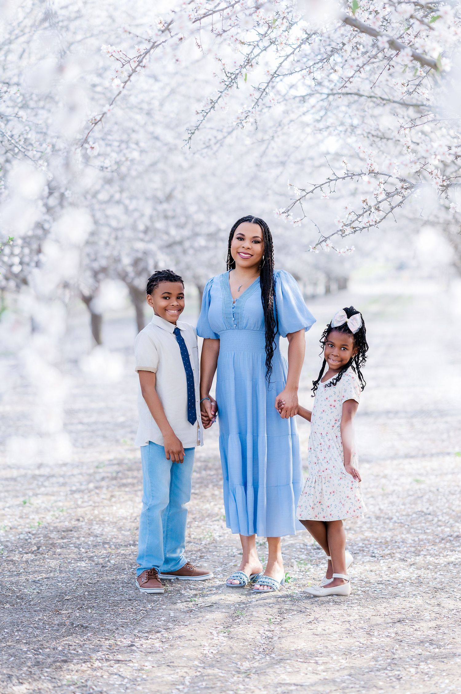 A family dressed in blue and white poses together beneath cherry blossoms.